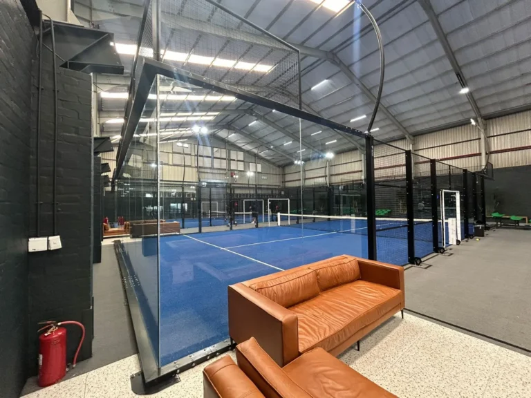 Glass-walled indoor court and courtside lounge at Arturf Padel Arena