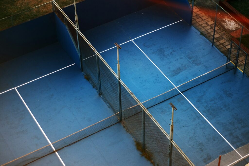 Aerial view of a blue padel court with mesh fencing and white court lines