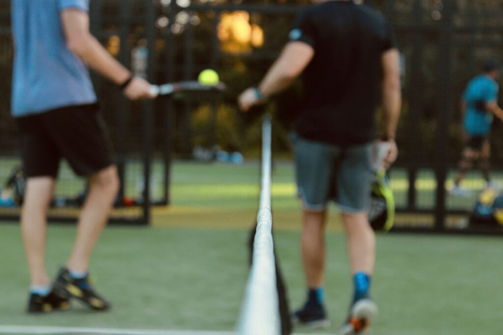 Padel players at the net during a doubles game on an outdoor court