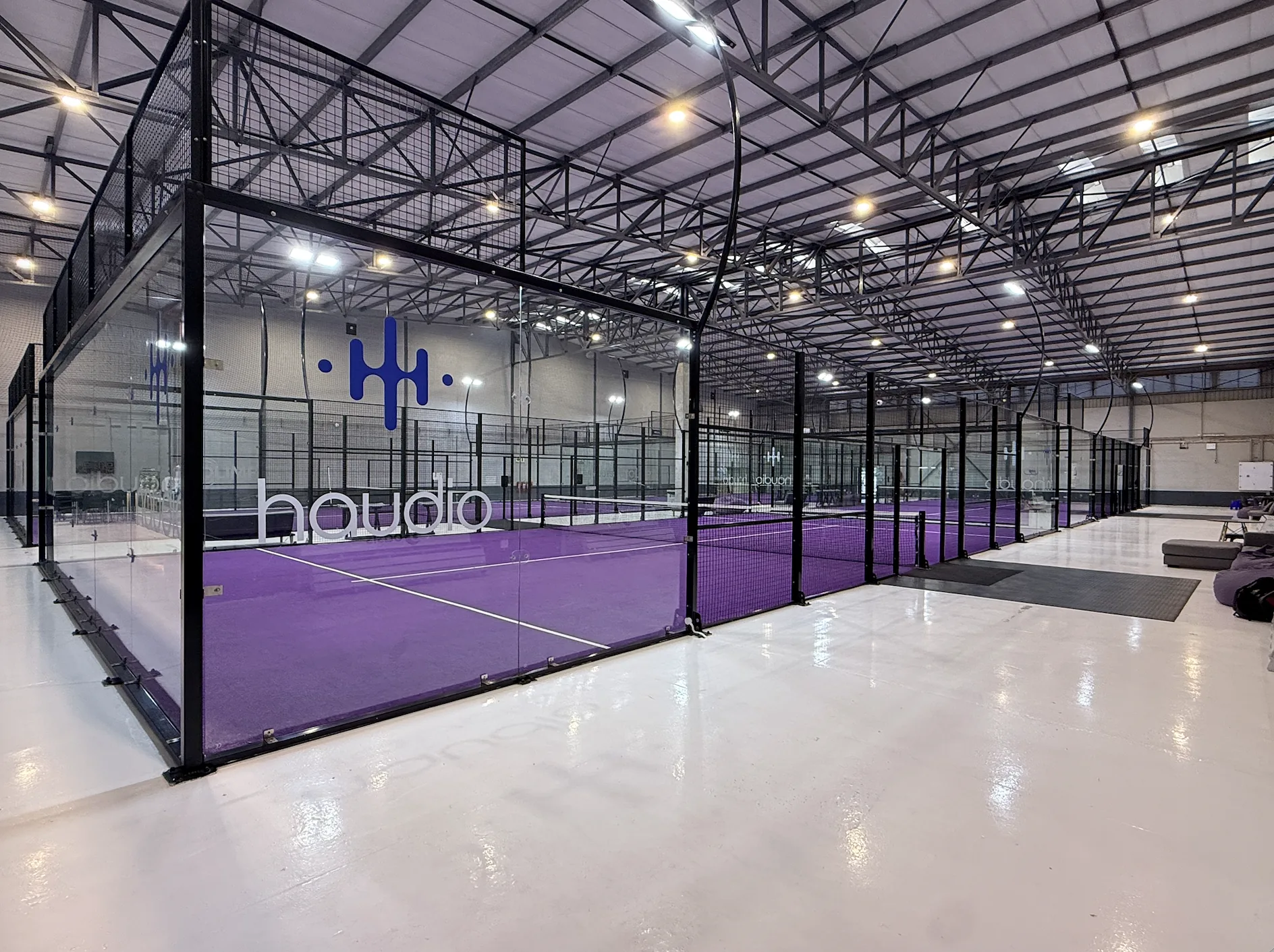 Glass-walled indoor padel court with purple turf at Eden Padel